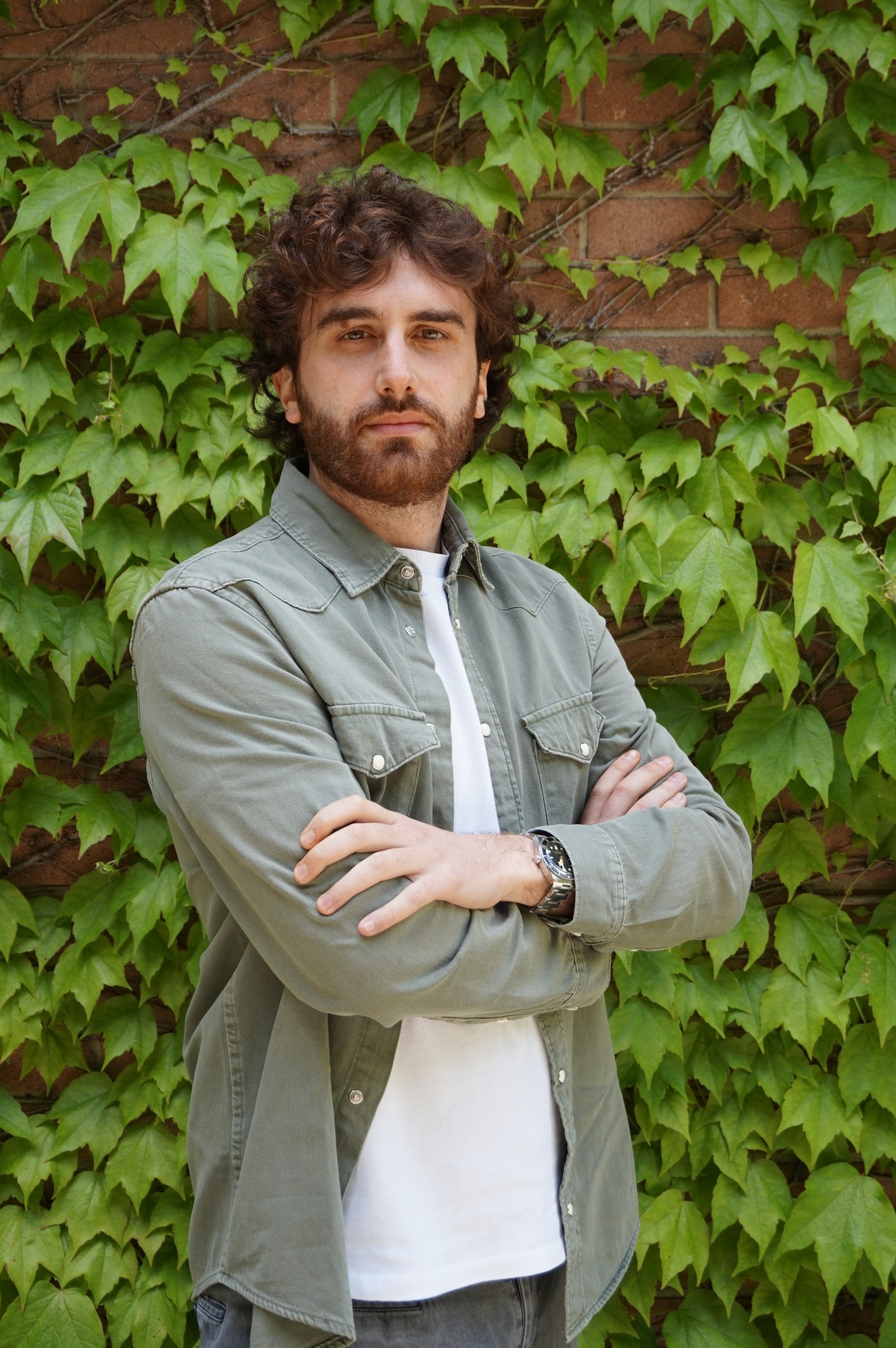 Lorenzo Baldini davanti a una parete ricoperta di vegetazione